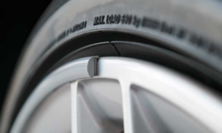 Close-up of a WHEELUV protector fitted to the rim of an alloy wheel, sitting against the tyre
